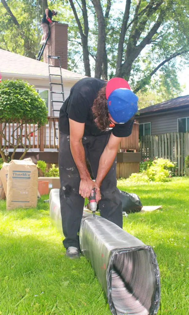 Worker Is Using A Drill On A Metal Chimney