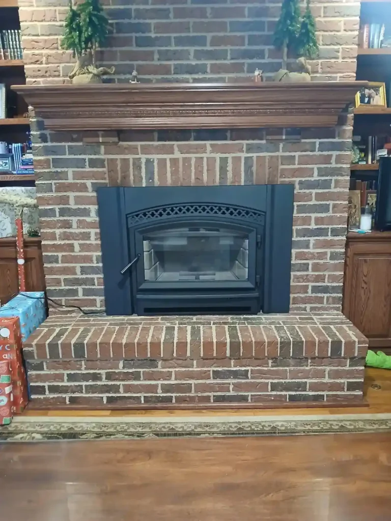 Red brick fireplace with wood insert and dark wood mantel